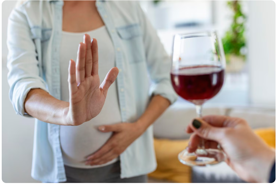 
Mujer embarazada rechazando una copa de vino tinto, símbolo de consumo no recomendado durante el embarazo.